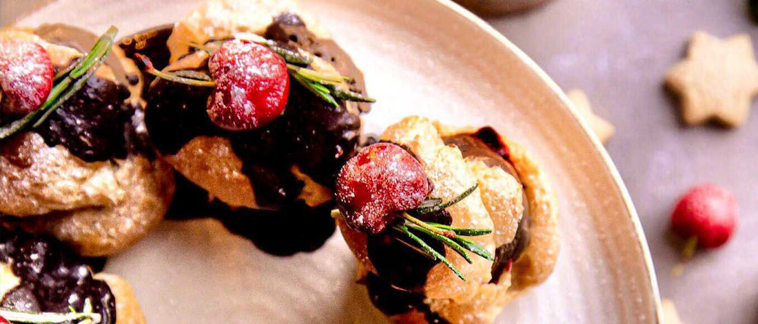 Profiteroles Filled With Colombian Chocolate & Hazelnut Ice Cream With Cherries On Top On Cake Stand Shown From Above
